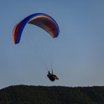 Paraglider turning to the right in front of a small hill